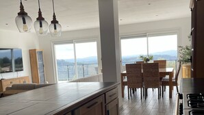 A modern kitchen with wooden cabinets, a large island, and a dining area with wicker chairs. - Villa Provençale Tout Confort Avec vue (Tanneron)