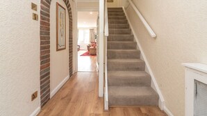 A hallway with a carpeted staircase, wooden flooring, and a brick archway. - Spacious Cosy Home Close To London Abbey Wood - Pass the Keys (London)