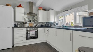 Eine moderne Küche mit weißen Schränken, einer Edelstahl-Dunstesse und einem eingebauten Backofen.