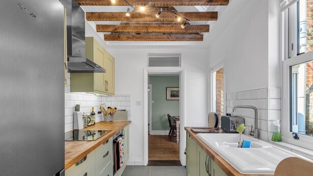 Eine moderne Küche mit einem Edelstahl-Kühlschrank, Holzbalken und einem großen Fenster.