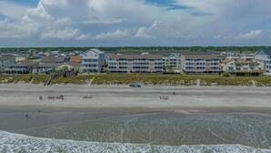 Un hôtel situé en bord de mer, composé de plusieurs bâtiments, avec une plage de sable fin et un ciel dégagé.