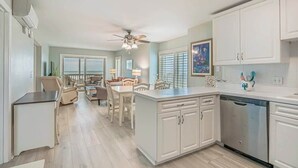 Une cuisine spacieuse avec des meubles blancs, un îlot central et un coin repas comprenant des chaises et une table.