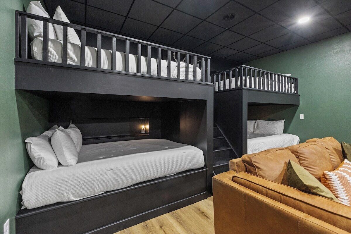 A room with bunk beds, a staircase, and a sofa.
