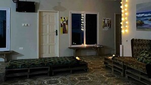 Un salon avec un sol à motifs, un ventilateur de plafond, un téléviseur et un canapé.