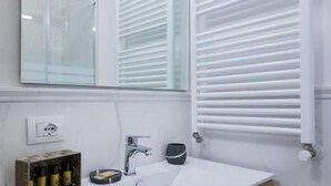 A modern bathroom with a white sink, a mirror, and a built-in heater. - VRooms All'Angolo Del Duomo (Florence)
