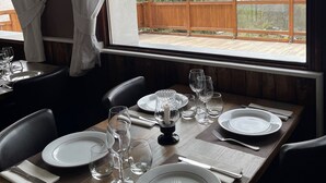 Une table à manger dressée pour deux personnes, avec vue sur les montagnes par la fenêtre.