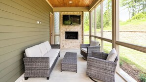 A covered patio with wicker furniture, a fireplace, and a ceiling fan. - The Mae, 3BR Luxe Home by Velvet Ditch Villas (Oxford)