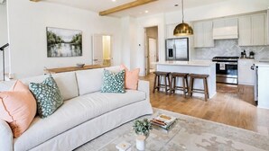 A modern kitchen with white cabinets, a stainless steel refrigerator, and a wooden ceiling. - The Mae, 3BR Luxe Home by Velvet Ditch Villas (Oxford)