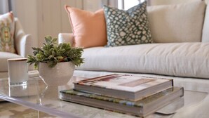 A living room with a sofa, cushions, a glass coffee table, a potted plant, and books. - The Mae, 3BR Luxe Home by Velvet Ditch Villas (Oxford)