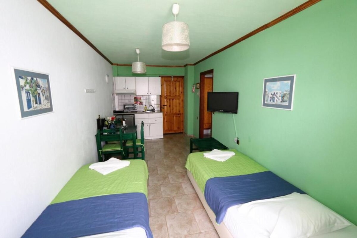 Une chambre avec deux lits, un coin cuisine, une table à manger et un téléviseur.