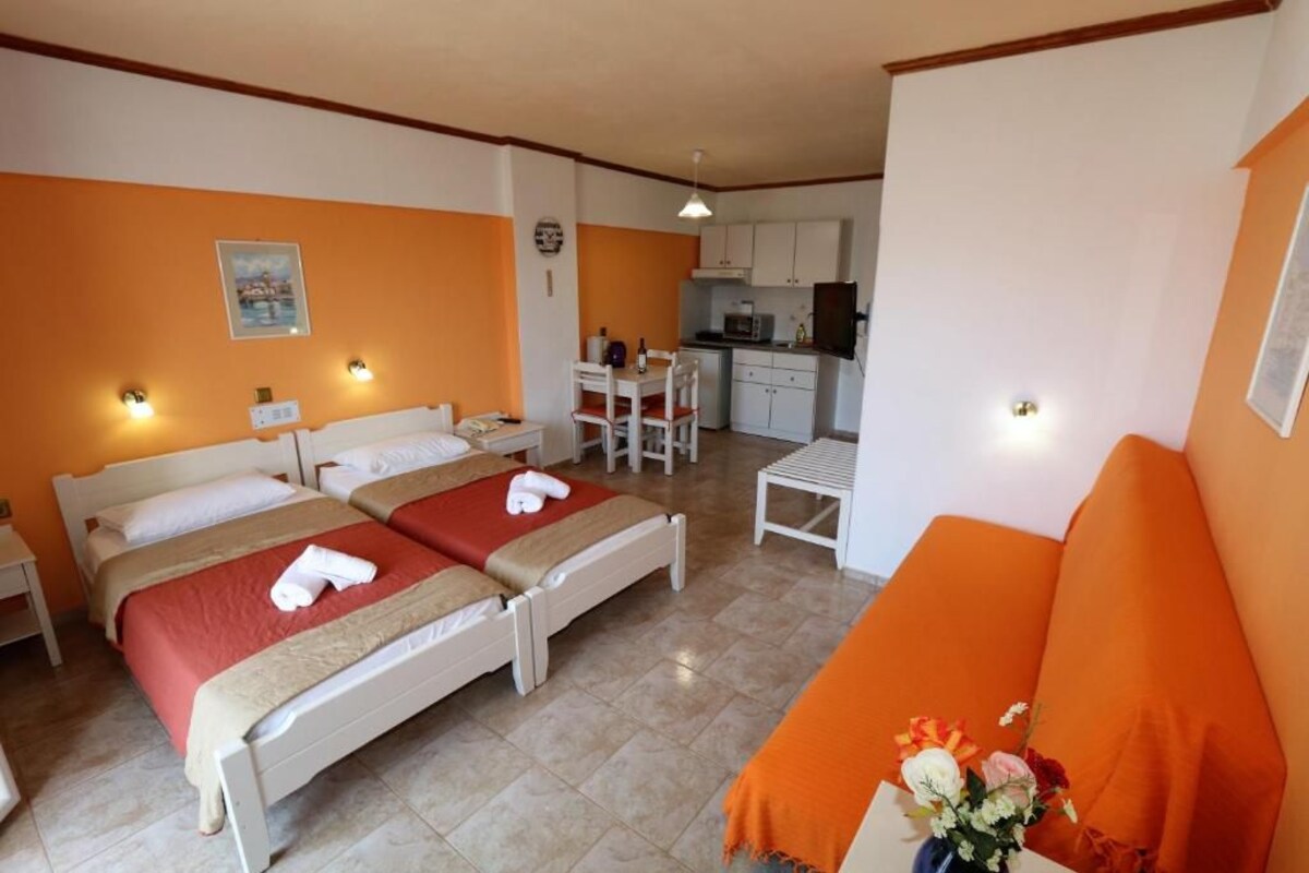 A hotel room with two beds, a kitchenette, and a dining area.