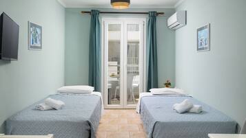 Habitación con dos camas, televisión y puerta corrediza que da a un balcón.