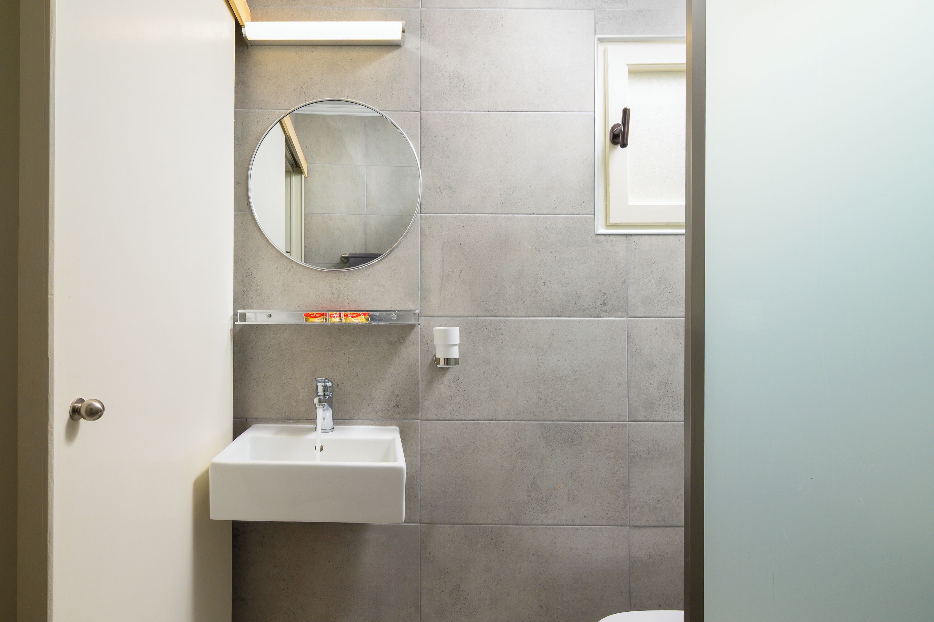 A bathroom with a round mirror, a white sink, and a towel rack.