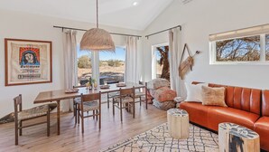 Een ruime woonkamer met een eettafel, leren bank en uitzicht op het omliggende landschap.