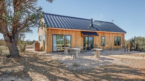 Een houten chalet met een metalen dak, grote glazen deuren en een terras.