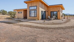Een modern houten huis met grote ramen en een overdekt terras.