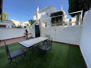 A patio with a table and chairs, a barbecue grill, and a white wall with a window. - Lovely holiday home located in the desirable area of Marbella, (Marbella)