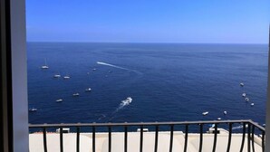 Un balcon avec vue sur l’océan et sur plusieurs bateaux.