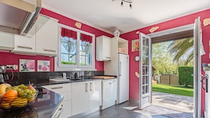 Cocina moderna con armarios blancos, encimera negra y pared roja.