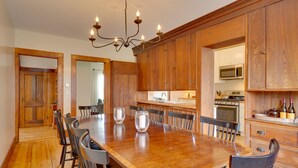 Un vaste espace dédié à la salle à manger, avec une grande table et des chaises en bois, un lustre et des meubles de rangement en bois.