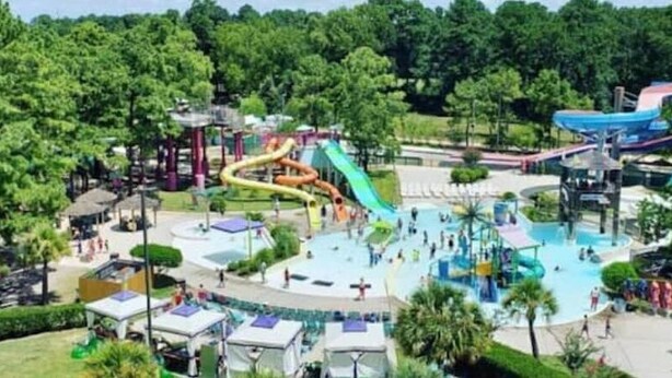 Un parc aquatique doté de nombreux toboggans et de plusieurs piscines, le tout entouré d’arbres.