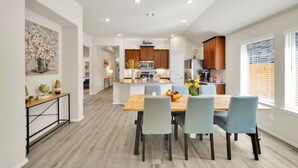 Une cuisine moderne avec des meubles en bois, un îlot central et un coin repas comprenant une table en bois et quatre chaises.