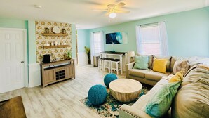 A living room with a sofa, coffee table, and decorative items. There is a dining area with a table and chairs.