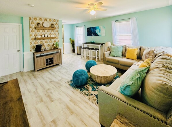A living room with a sofa, coffee table, and decorative items. There is a dining area with a table and chairs. - Newly Renovated 3BD/2BTH, 1 BLK to Beach (Brigantine)