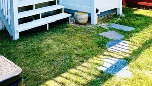 A white house with a front porch, a wooden gate, and a red fence.