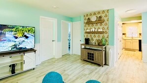 A living room with a television, a wooden cabinet, and a patterned wall.