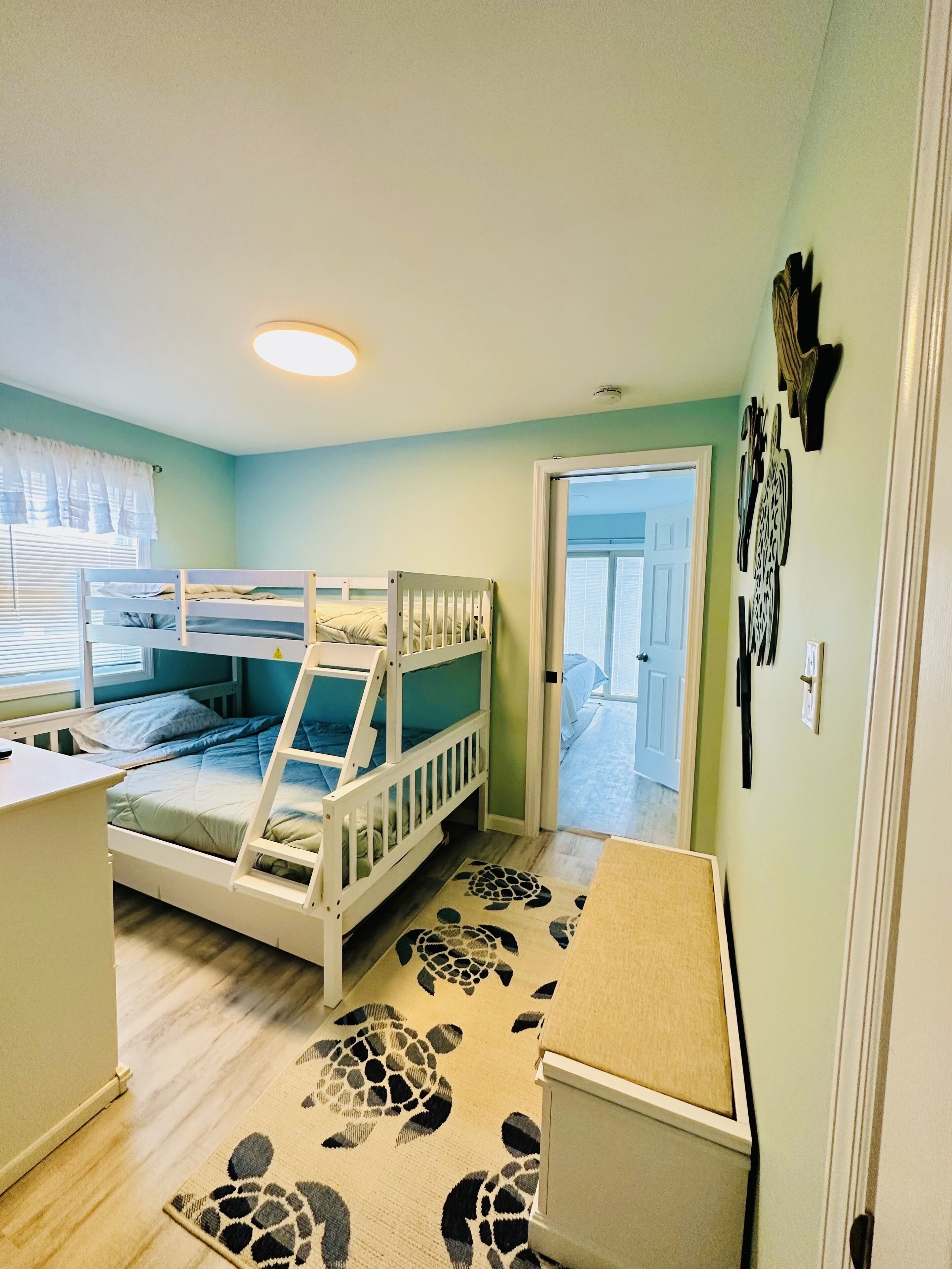 Ein Kinderzimmer mit Etagenbetten, einem Schreibtisch und einem Teppich mit Schildermotiv.