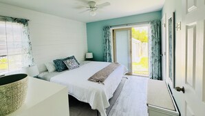 A bedroom with a bed, a ceiling fan, a window with curtains, and a door leading outside.