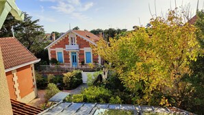 A building with a red roof and blue doors, surrounded by greenery and a clear sky. - Hôtel Michelet Plage (Soulac-sur-Mer)