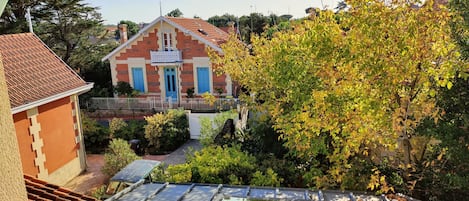 A building with a red roof and blue doors, surrounded by greenery and a clear sky.