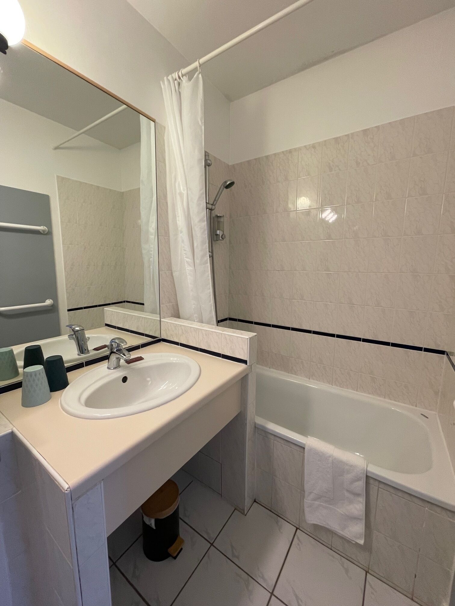 A modern bathroom with a white sink, mirror, and bathtub.