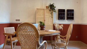 A dining area with wicker chairs, a round table, a hanging rattan light fixture, and wall-mounted key displays. - Hôtel Michelet Plage (Soulac-sur-Mer)