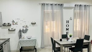 Eine moderne Küche mit Essbereich, ausgestattet mit einem Tisch, Stühlen, einer Bank und einem an der Wand befestigten Regal mit Küchenutensilien.