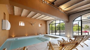 Ein Hallenbad mit Holzliegen und einer Steinwand.