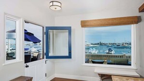 A room with a view of a marina, a wooden bench, and a door leading to a balcony.