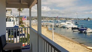 A balcony with a view of a marina, boats, and a sandy beach.