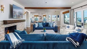 A spacious living room with a fireplace, a large sofa set, and a view of the marina.
