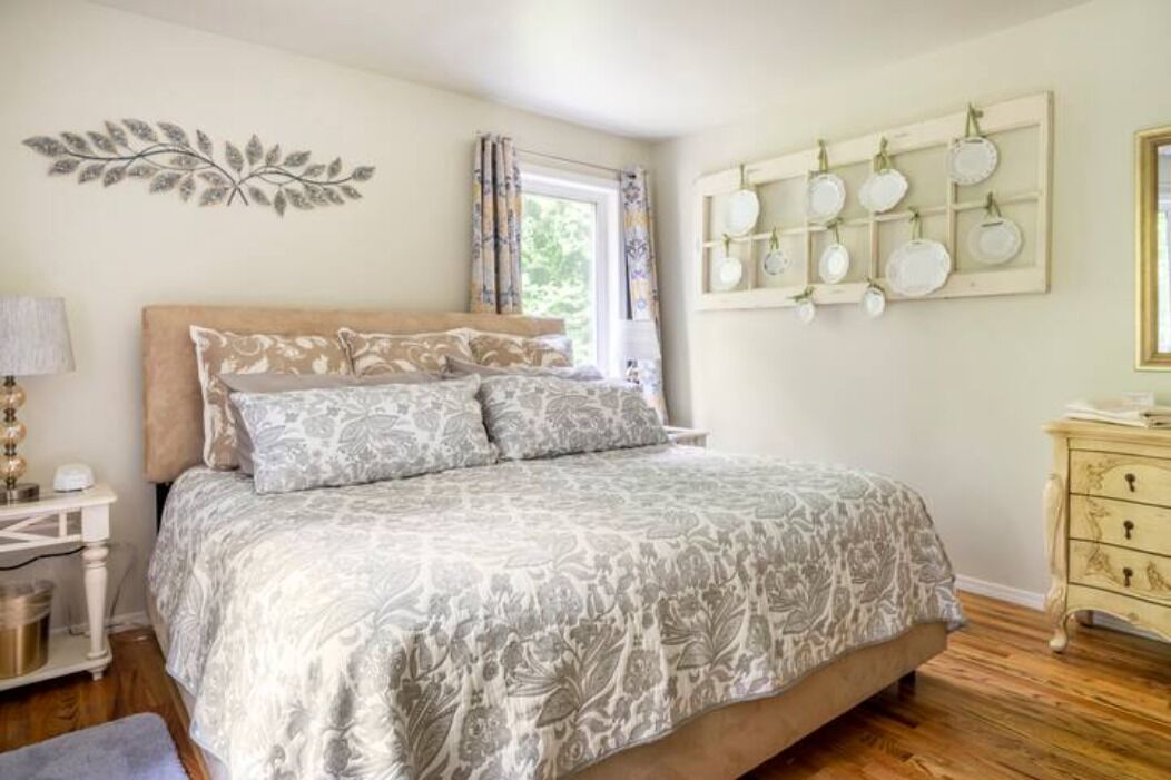 Een slaapkamer met een bed, nachtkastje, dressoir en een wandplank.