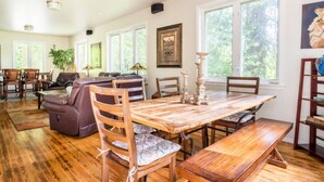 A spacious dining area with a wooden table and benches, surrounded by chairs and a sofa. - Magical Private House in Forest w/Hot Tub. Near Wineries! (Woodinville)