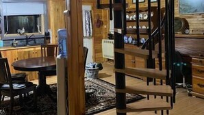 A wooden interior with a spiral staircase, a dining area, and a kitchen. - Forest Side Solar Powered Cabin with Nature Trails (Norfolk)