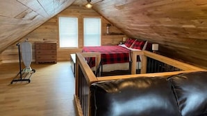 A cozy attic bedroom with a loft bed, wooden walls, and a small window. - Forest Side Solar Powered Cabin with Nature Trails (Norfolk)