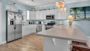 A modern kitchen with white cabinetry, stainless steel appliances, and a large island. - Antigua Blue - Private Pool - Walk to Beach - 6BR/7BA (North Myrtle Beach)