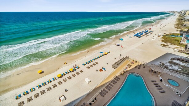 Un complexe hôtelier de bord de mer doté d’une piscine, de chaises longues et de parasols.