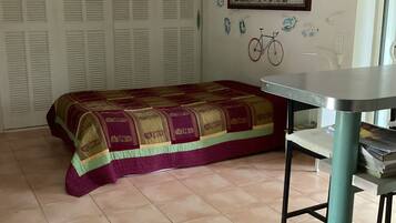 Een slaapkamer met een bed, een tafel en een fiets aan de muur.