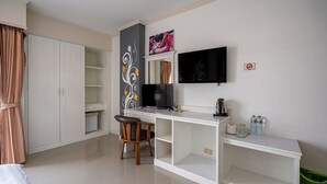 Hotellihuone, jossa on sänky, työpöytä tuolilla, televisio, vaatekaappi ja roskakori.