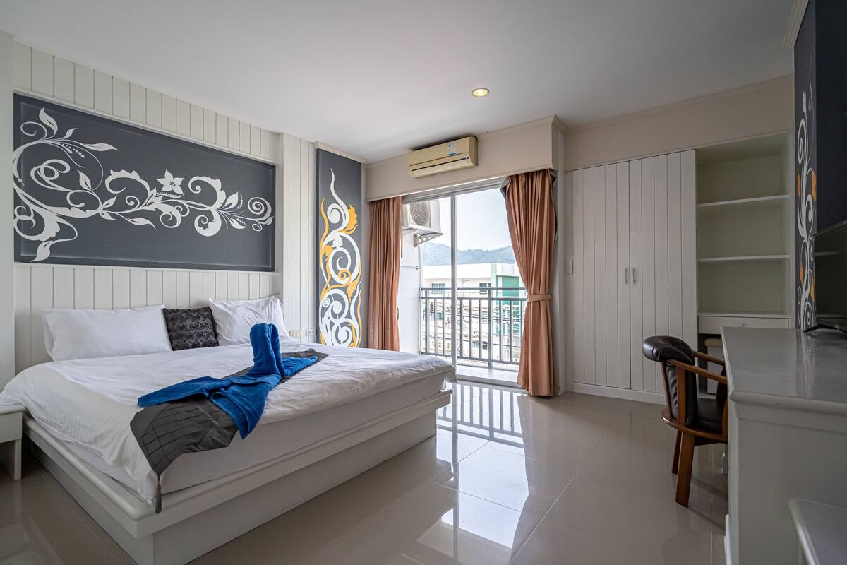 A hotel room with a bed, a desk, and a view of the outside.